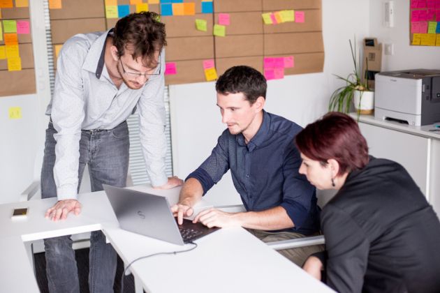 Nicolas, François et Sonia devant un ordinateur portable à l'agence Oniti.