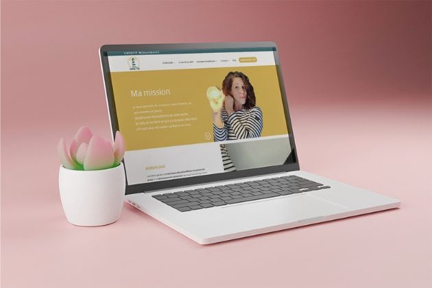 laptop sur fond rose affichant le site internet d'Audrey Mée