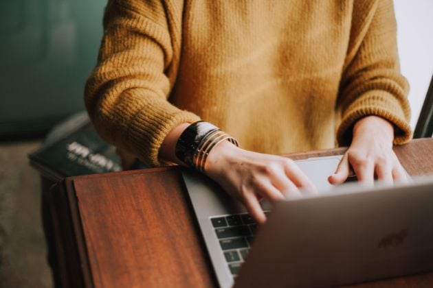 Une femme écrit sur un ordinateur portable