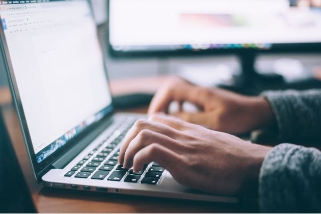 Des mains tapent sur un clavier d'ordinateur portable