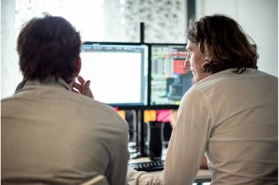 Julien et François semblant réfléchir devant un double écran d'ordinateur